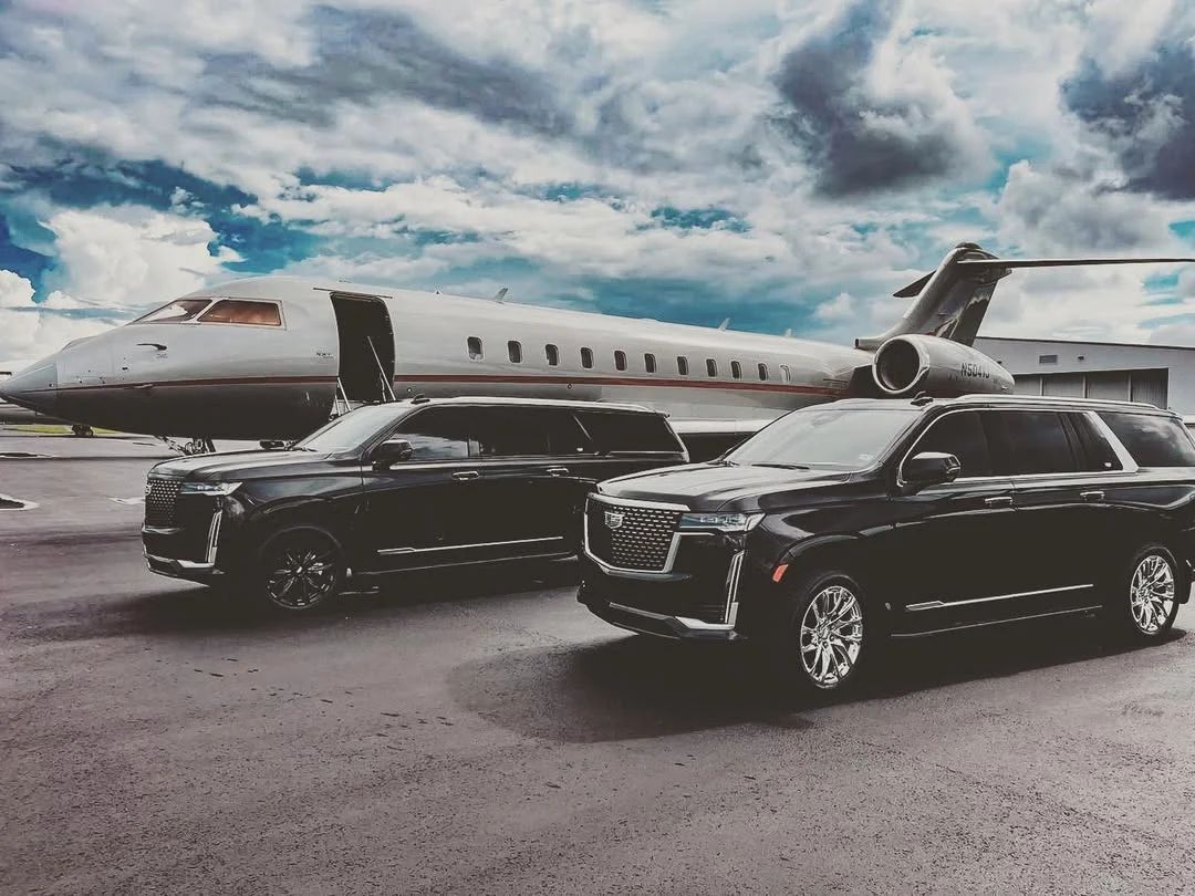 Black Aura Palm SUVs waiting beside a private jet for arriving riders and owners