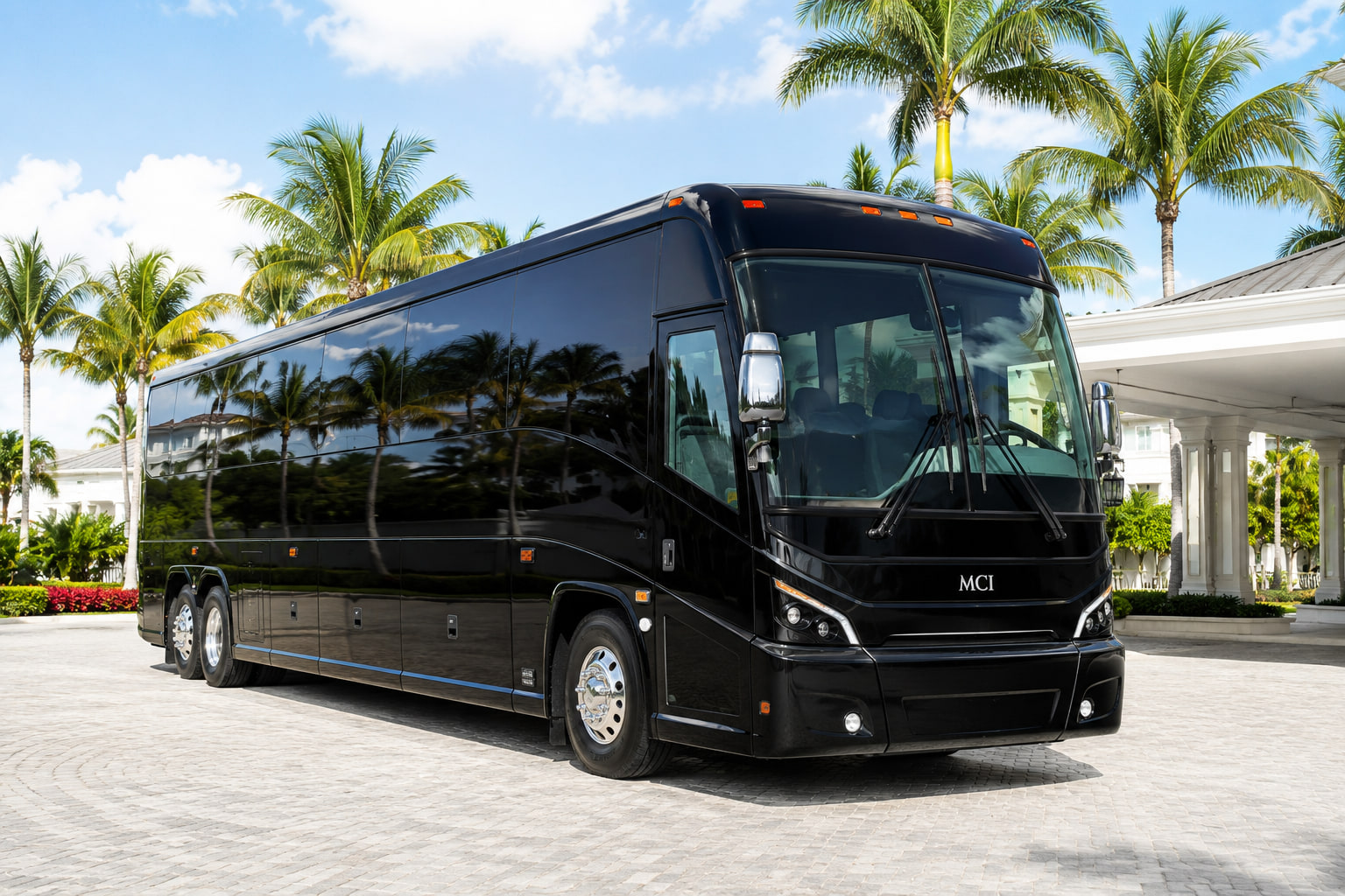 Black 55-passenger charter bus on a palm-lined driveway in South Florida