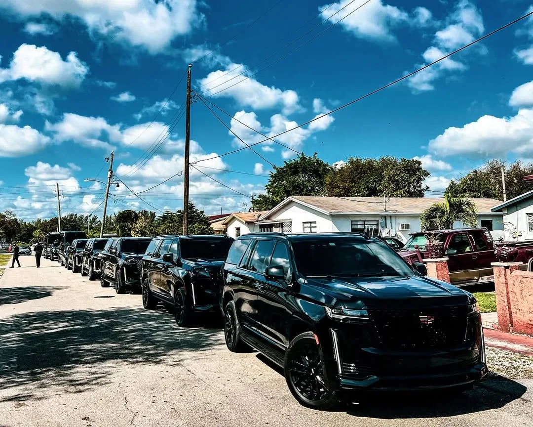 A line of black Aura Palm SUVs on a South Florida residential street in daylight